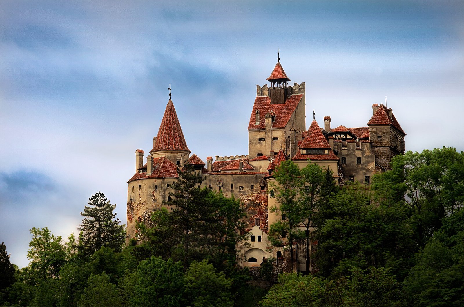 Bran Castle's white towers and red roofs on a rocky hill
